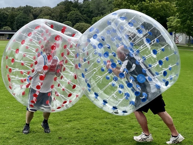 Two players colliding in bumper balls on grass field