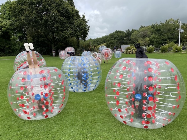 Two players colliding in bumper balls on grass field